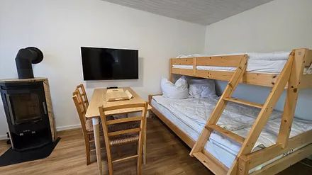 Wohnzimmer mit Sitzecke und Kaminofen und Etagenbett