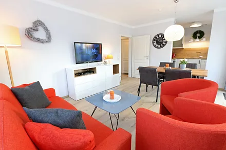 Wohnzimmer mit Schlafcouch (1,60 m x 2,00 m, Aufbettung für 2 Personen), zwei Sessel, Couchtisch, Smart-TV, DVD-Player, Radio mit CD-Player sowie verschiedene Lektüren für Leseratten