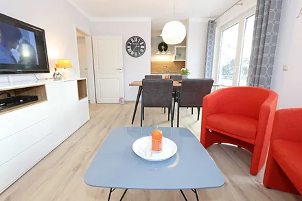 Wohnzimmer mit Schlafcouch (1,60 m x 2,00 m, Aufbettung für 2 Personen), zwei Sessel, Couchtisch, Smart-TV, DVD-Player, Radio mit CD-Player sowie verschiedene Lektüren für Leseratten