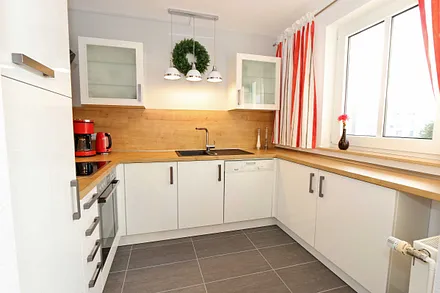 moderne Küchenzeile mit Ceranfeld, Backofen, Kühlschrank mit Eisfach, Geschirrspüler, Mikrowelle, Wasserkocher, Toaster, Kaffeemaschine und diverse Kochutensilien