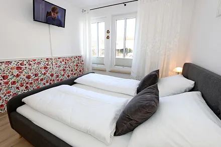 Schlafzimmer mit Doppelbett (1,80 m x 2,00 m), verstellbaren Lattenrosten, Nachttischablagen, Kleiderschrank sowie ein TV