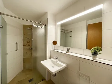 Badezimmer mit ebenerdiger Dusche, WC, Waschbecken und Fön 