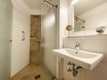 Badezimmer mit ebenerdiger Dusche, WC, Waschbecken und Fön 