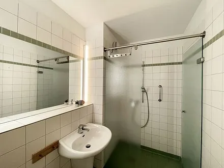 Badezimmer mit ebenerdiger Dusche, WC, Waschbecken und Fön