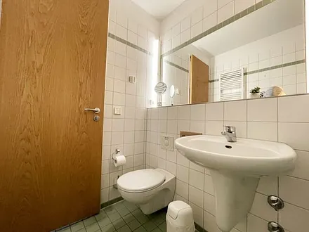 Badezimmer mit ebenerdiger Dusche, WC, Waschbecken und Fön