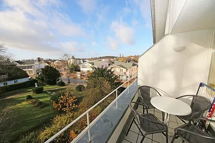 bestuhlte, sonnige Loggia (West) mit Blick auf einen kleinen Park