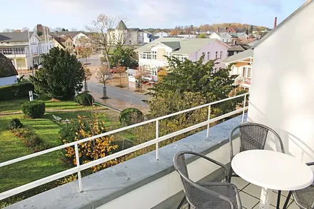 bestuhlte, sonnige Loggia (West) mit Blick auf einen kleinen Park