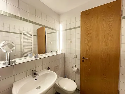 Badezimmer mit ebenerdiger Dusche, WC, Waschbecken und Fön