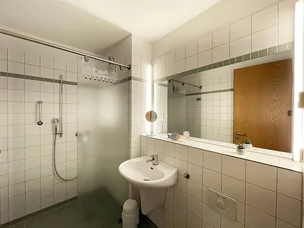 Badezimmer mit ebenerdiger Dusche, WC, Waschbecken und Fön