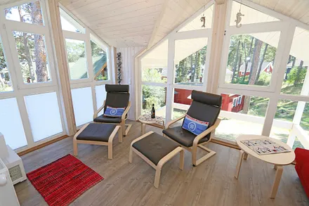 lichtdurchflutete Galerie (ohne Vorhänge) mit Couch, Relaxsesseln und Smart TV