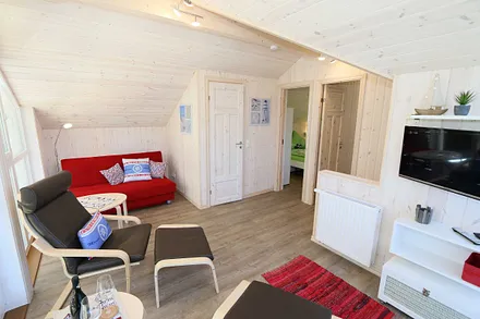 lichtdurchflutete Galerie (ohne Vorhänge) mit Couch, Relaxsesseln und Smart TV