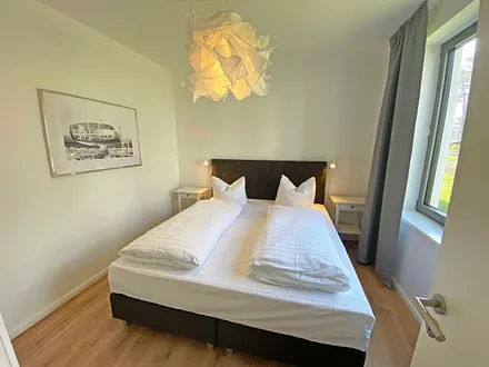 Schlafzimmer mit einem Boxspringbett (1,80 m x 2,00 m), Beistelltischen mit Nachtlicht, einem Kleiderschrank sowie lichtdichte Vorhänge und Insektenschutzgitter