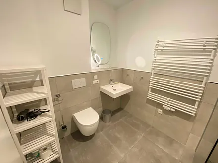 innenliegendes Bad mit einem Waschtisch, beheiztem und beleuchtetem Spiegel, Handtuchheizung, Fön, Kosmetikspiegel, WC sowie eine große ebenerdige Klarglas-Dusche mit Regenduschkopf