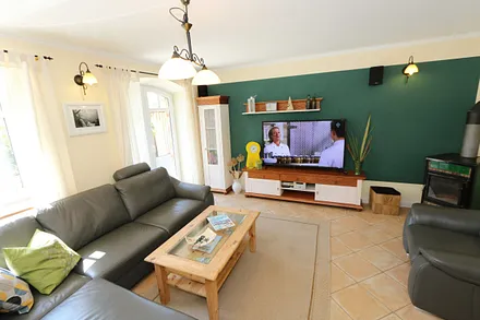 gemütlicher Wohnbereich mit einer großen Couchecke, Couchtisch, Leselampe, Sideboard, Flachbild-TV und Mini-Stereo-Anlage
