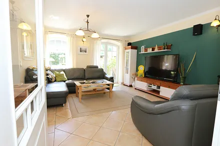 gemütlicher Wohnbereich mit einer großen Couchecke, Couchtisch, Leselampe, Sideboard, Flachbild-TV und Mini-Stereo-Anlage