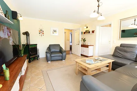 gemütlicher Wohnbereich mit einer großen Couchecke, Couchtisch, Leselampe, Sideboard, Flachbild-TV und Mini-Stereo-Anlage