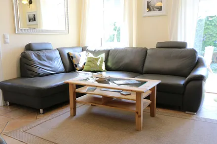 gemütlicher Wohnbereich mit einer großen Couchecke, Couchtisch, Leselampe, Sideboard, Flachbild-TV und Mini-Stereo-Anlage