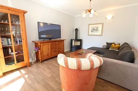 Wohnbereich mit großer Couchecke, Couchtisch, Leselampe, Sideboard, Smart-TV und Mini-Stereo-Anlage