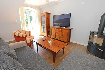 Wohnbereich mit großer Couchecke, Couchtisch, Leselampe, Sideboard, Smart-TV und Mini-Stereo-Anlage