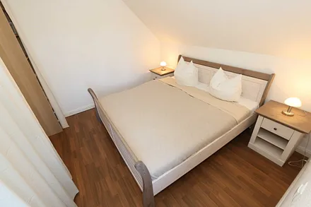Schlafzimmer mit Doppelbett (1,80 m x 2,00 m), verstellbaren Lattenrosten, Nachttischablagen, Kleiderschrank, Verdunklungsmöglichkeit und Smart-TV
