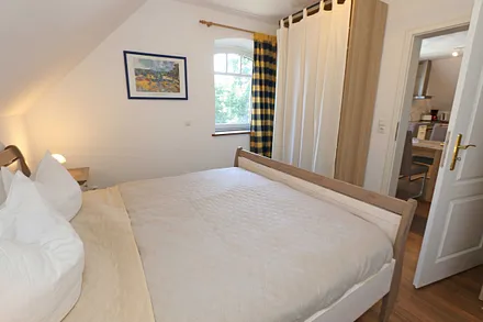 Schlafzimmer mit Doppelbett (1,80 m x 2,00 m), verstellbaren Lattenrosten, Nachttischablagen, Kleiderschrank, Verdunklungsmöglichkeit und Smart-TV