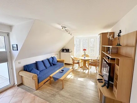 Wohnbereich mit Couch, Couchtisch sowie TV-Board, Leselampe, LCD-Flachbildschirm, Blu-Ray-Player und Mini-Stereo-Anlage sowie Insektenschutzgitter