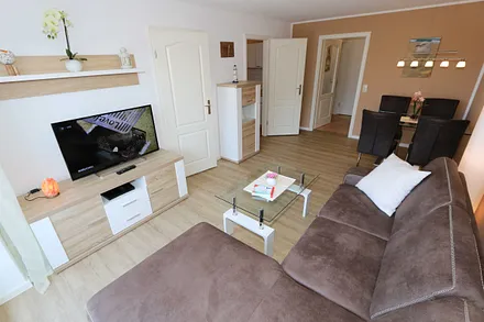 Wohnbereich mit gemütlicher Couch (Aufbettung für 3. Person 1,20 m x 2,00 m), Leselampe, Couchtisch, TV-Board mit Smart-TV, Blu-Ray-Player und Mini-Stereo-Anlage 