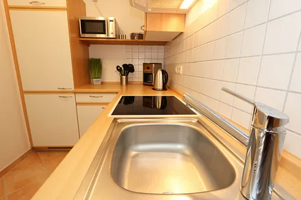 Küche mit Geschirrspüler, Cerankochfeld, Backofen, Kühlschrank mit Gefrierfächer, Mikrowelle, Kaffeemaschine, Senseopad-Maschine, Wasserkocher, Toaster sowie diverse Küchenutensilien