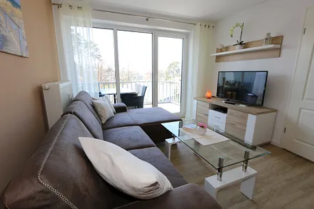 Wohnbereich mit gemütlicher Couch (Aufbettung für 3. Person 1,20 m x 2,00 m), Leselampe, Couchtisch, TV-Board mit Smart-TV, Blu-Ray-Player und Mini-Stereo-Anlage