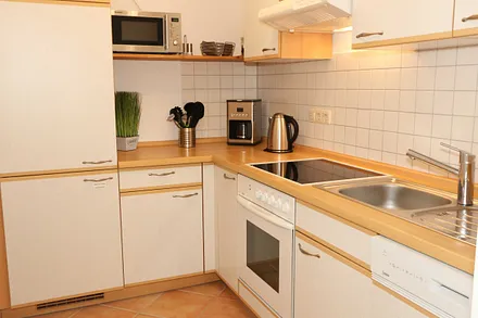 Küche mit Geschirrspüler, Cerankochfeld, Backofen, Kühlschrank mit Gefrierfächer, Mikrowelle, Kaffeemaschine, Senseopad-Maschine, Wasserkocher, Toaster sowie diverse Küchenutensilien