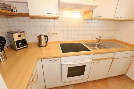 Küche mit Geschirrspüler, Cerankochfeld, Backofen, Kühlschrank mit Gefrierfächer, Mikrowelle, Kaffeemaschine, Senseopad-Maschine, Wasserkocher, Toaster sowie diverse Küchenutensilien