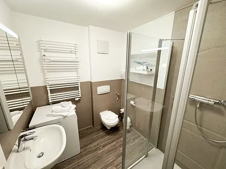 Badezimmer mit Eckdusche, Waschplatz, WC, Fön, Kosmetikspiegel, Handtuchheizkörper und Waschmaschine (Nutzung inklusive)