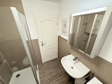 Badezimmer mit Eckdusche, Waschplatz, WC, Fön, Kosmetikspiegel, Handtuchheizkörper und Waschmaschine (Nutzung inklusive)