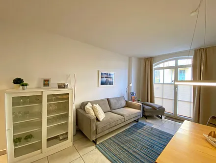 Wohnbereich mit bodentiefen Fenstern, 3-Sitzer-Couch, Couchtisch, Smart-TV, DVD-Player, Radio mit CD-Player und USB-Anschluss sowie eine Alexa-Box