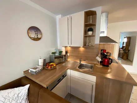 angrenzende Pantry-Küche mit Edelstahlspüle, 4-Zonen-Cerankochfeld, Kühlschrank mit Gefrierfach, Geschirrspüler, Mikrowelle, Dunstabzugs-Kombination, Kaffeemaschine, Wasserkocher und Toaster