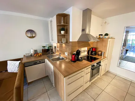 angrenzende Pantry-Küche mit Edelstahlspüle, 4-Zonen-Cerankochfeld, Kühlschrank mit Gefrierfach, Geschirrspüler, Mikrowelle, Dunstabzugs-Kombination, Kaffeemaschine, Wasserkocher und Toaster