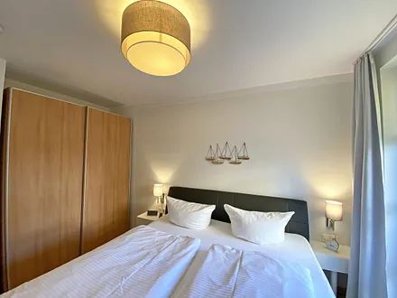 Schlafzimmer mit Echtleder-Doppelbett in Komforthöhe (2 x 0,90 m x 2,00 m), mit Nachttischablagen, Insektenschutzgittern, Verdunklungsmöglichkeit und einen großem Kleiderschrank