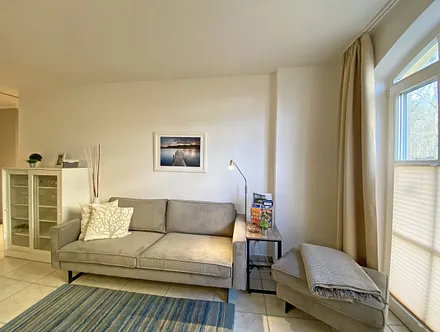 Wohnbereich mit bodentiefen Fenstern, 3-Sitzer-Couch, Couchtisch, Smart-TV, DVD-Player, Radio mit CD-Player und USB-Anschluss sowie eine Alexa-Box