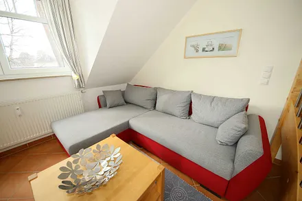 Wohnzimmer mit gemütlicher Couchecke, Couchtisch und Leselampe sowie ein Smart-TV und ein DAB-Radio mit CD-Player