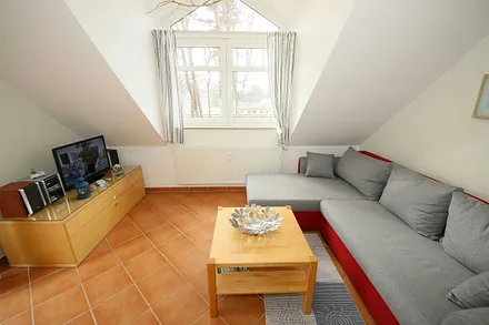 Wohnzimmer mit gemütlicher Couchecke, Couchtisch und Leselampe sowie ein Smart-TV und ein DAB-Radio mit CD-Player