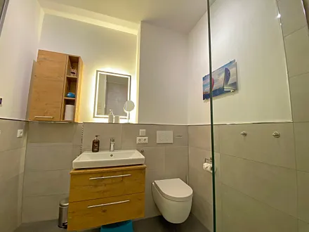 innenliegendes Badezimmer mit Waschtisch, Wandspiegel, ebenerdiger Regendusche, WC, Fön und Handtuchtrockner