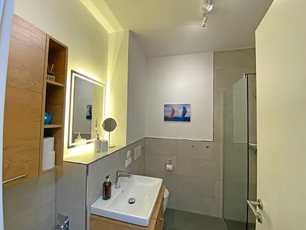 innenliegendes Badezimmer mit Waschtisch, Wandspiegel, ebenerdiger Regendusche, WC, Fön und Handtuchtrockner