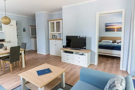 offener Wohnbereich mit bequemer Couch (Aufbettung 3. Person 1,60 m x 2,00 m), Sessel, Couchtisch, Stehlampe, Sideboard, Vitrine, Smart-TV sowie ein DAB Radio mit Bluetooth