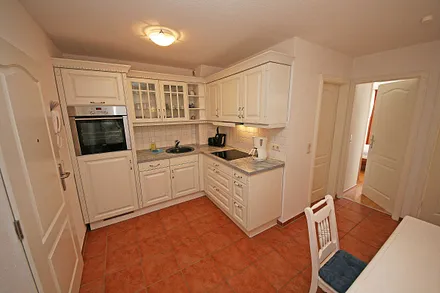 offene Küchenzeile mit Ceranfeld, Backofen, Geschirrspüler, Kühlschrank, Kaffeemaschine, Wasserkocher, Toaster sowie diverse Küchenutensilien