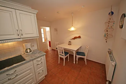 offene Küchenzeile mit Ceranfeld, Backofen, Geschirrspüler, Kühlschrank, Kaffeemaschine, Wasserkocher, Toaster sowie diverse Küchenutensilien