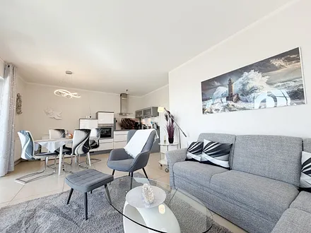 Wohnbereich mit Couch, Sessel,  Couchtisch und Smart-TV