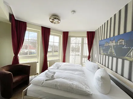 Schlafzimmer mit Doppelbett, Sessel und Kleiderschrank