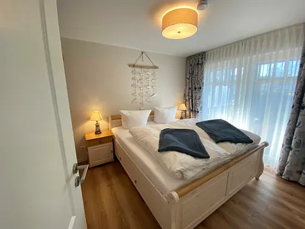 Schlafzimmer mit Doppelbett (1,80 m x 2,00 m), Nachttischablagen mit Lampen und einen Kleiderschrank