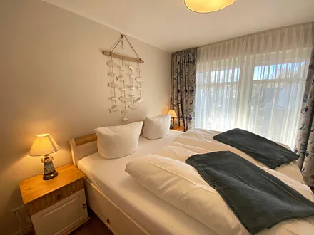 Schlafzimmer mit Doppelbett (1,80 m x 2,00 m), Nachttischablagen mit Lampen und einen Kleiderschrank