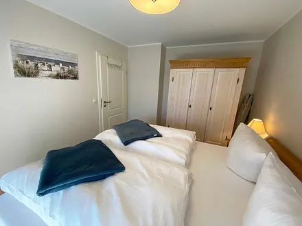 Schlafzimmer mit Doppelbett (1,80 m x 2,00 m), Nachttischablagen mit Lampen und einen Kleiderschrank